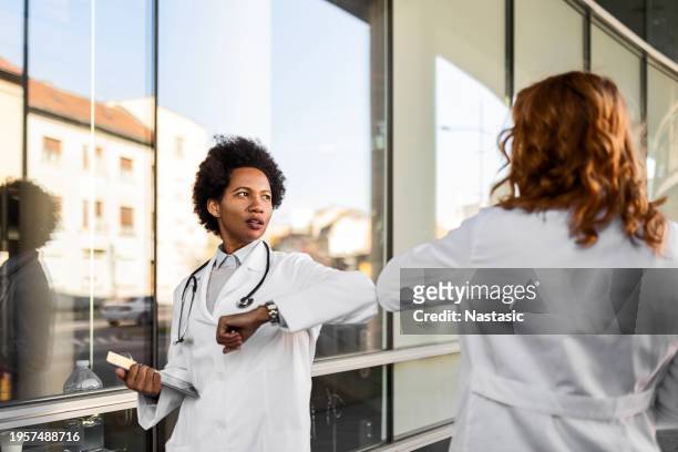 profesionales de la salud femeninas chocando codos - avoiding handshakes fotografías e imágenes de stock