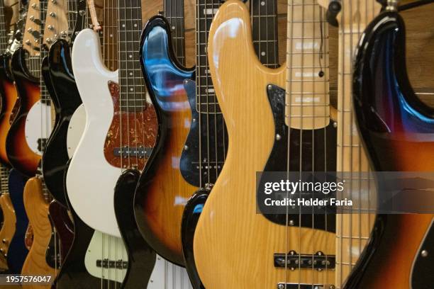 close-up of some electric double basses hanging by the hand - elektrogitarre stock-fotos und bilder