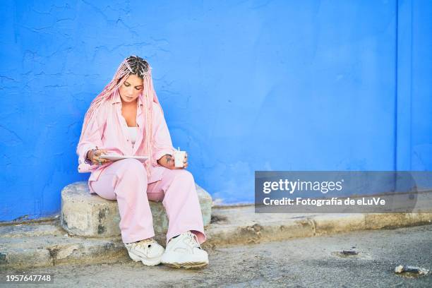 woman sitting on a step in front of a blue wall - half time stock pictures, royalty-free photos & images