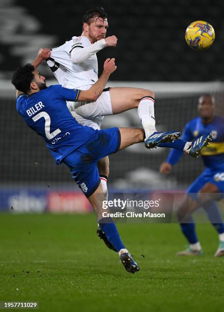 Alex Gilbey of MK Dons and Huseyin Biler of AFC Wimbledon battle for the ball in the air during the Sky Bet League Two match between Milton Keynes...