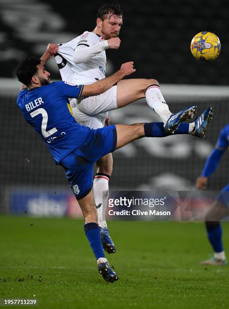 Alex Gilbey of MK Dons and Huseyin Biler of AFC Wimbledon battle for the ball in the air during the Sky Bet League Two match between Milton Keynes...