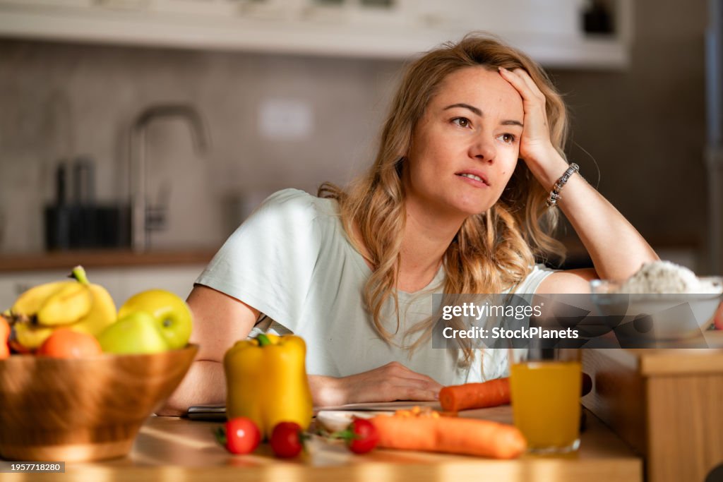 A tired woman is trying to prepare lunch while sitting in the kitchen