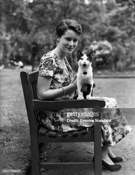 Countess Bunny Esterhazy sits on a bench with her cat, UK, 20th June 1955.