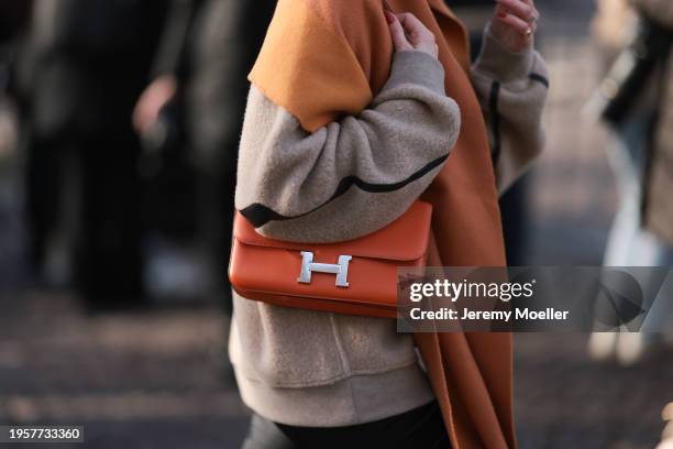 Guest is seen outside Hermes show wearing a orange Hermes constance handbag with palladium hardware during the Menswear Fall/Winter 2024/2025 as part...