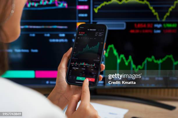 over the shoulder view of young woman using online banking and making financial investment with smartphone. cryptocurrency concept. - börshandlare bildbanksfoton och bilder