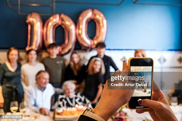 senior woman celebrating hundred years party with family together. - 100-jarig-jubileum stockfoto's en -beelden