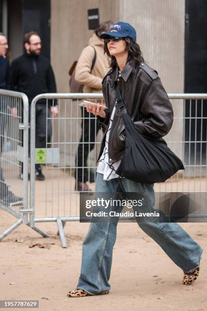 Guest wears brown leather jacket, baggy jeans, blue hat, leopard print flat shoes, outside Chanel, during the Haute Couture Spring/Summer 2024 as...