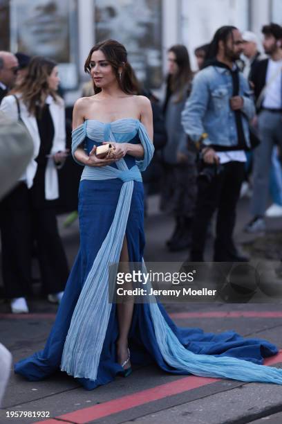 Myrna Al Haddad seen wearing silver diamond earrings, blue / light blue off-shoulder couture long dress and Celine gold leather pattern bag and blue...