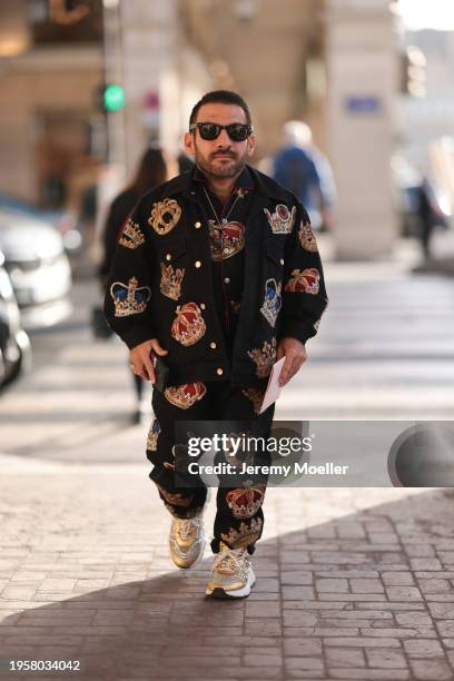 Dimitris Tsertsidis seen wearing Ray-Ban black Wayfarer sunglasses, gold / colorful necklace, Dolce & Gabanna black / colorful crown print pattern...