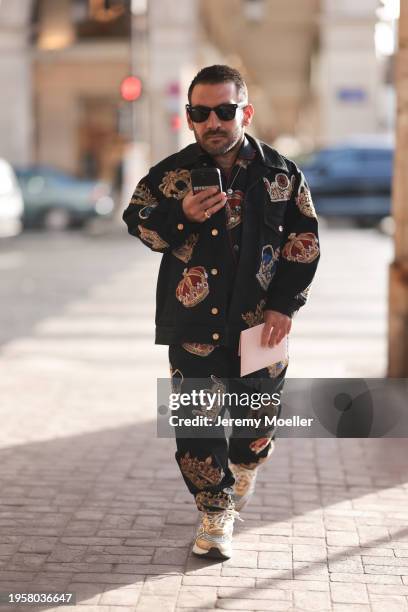 Dimitris Tsertsidis seen wearing Ray-Ban black Wayfarer sunglasses, gold / colorful necklace, Dolce & Gabanna black / colorful crown print pattern...