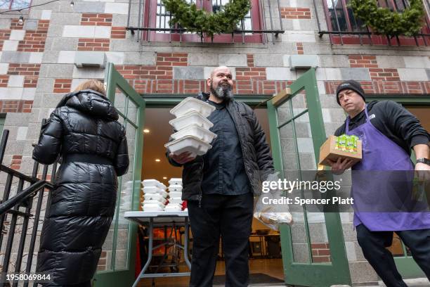 Volunteers hand out meals to a community composed of mostly newly arrived migrants at Trinity Services and Food For the Homeless, across from...