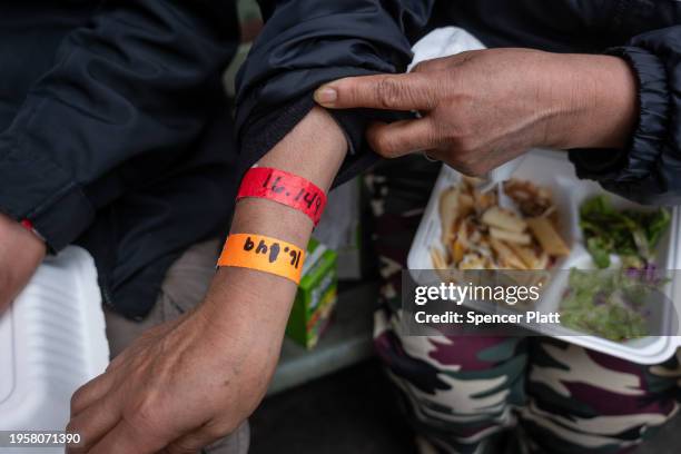 Peruvian woman displays a wrist ban used for processing while receiving an afternoon meal from Trinity Services and Food For the Homeless, across...
