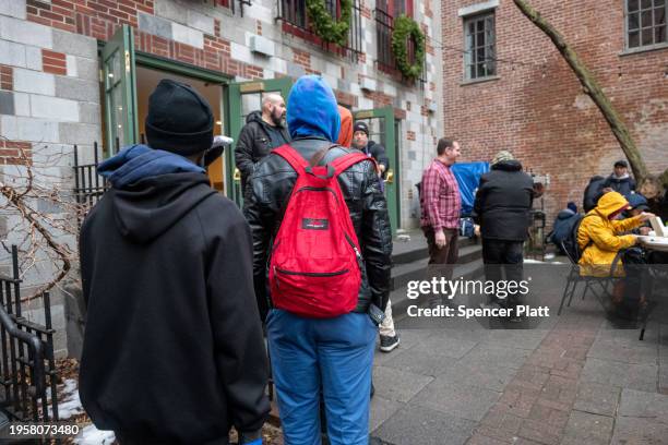 People, mostly newly arrived migrants, receive an afternoon meal from Trinity Services and Food For the Homeless, across from Tompkins Square Park on...