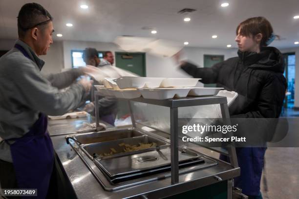 Volunteers prepare meals for a community composed of mostly newly arrived migrants at Trinity Services and Food For the Homeless, across from...