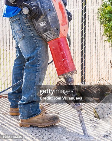 Construction Worker Precision Breaking Cement Floor with Jackhammer.