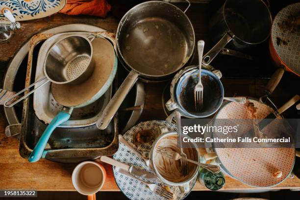 top down image of a pile of dirty dishes and saucepans sitting on a countertop in a kitchen - caos foto e immagini stock