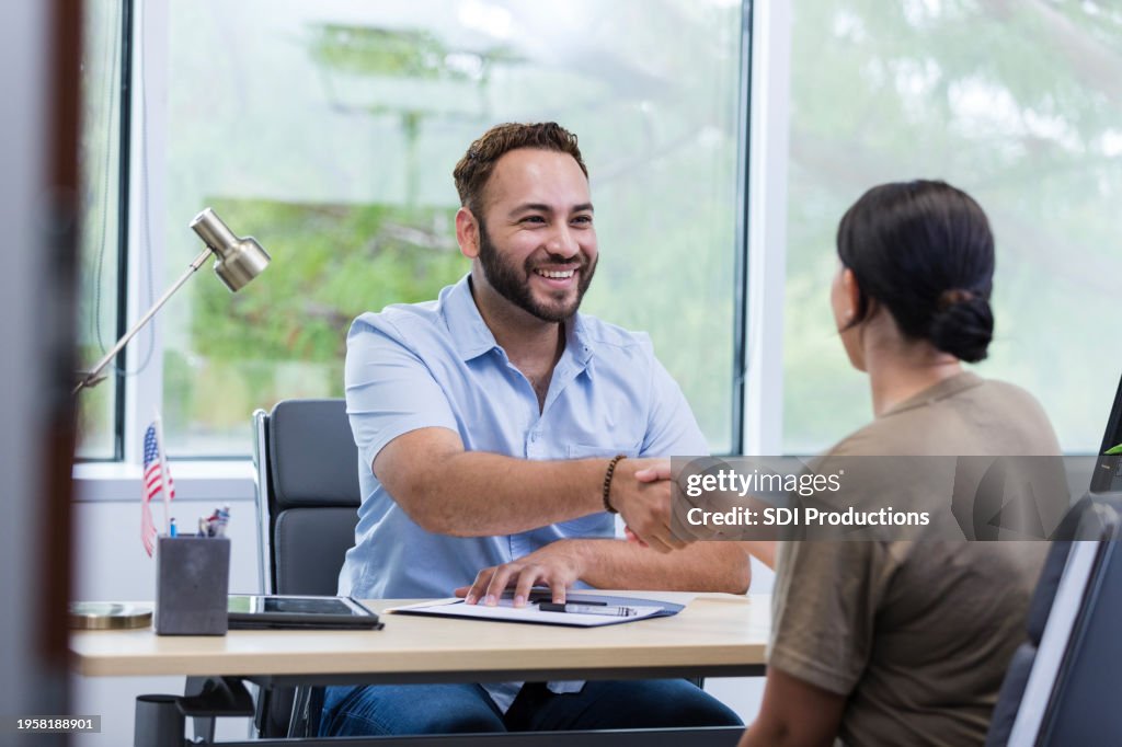 Male financial planner shakes hands with unrecognizable female soldier
