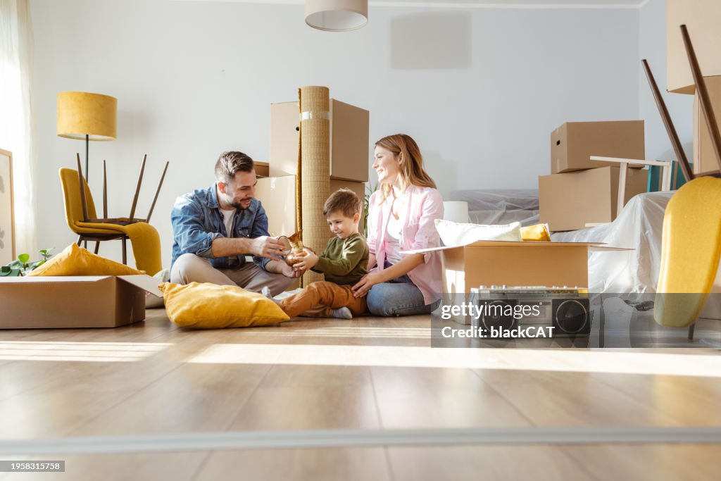 Familia joven feliz desempacando pertenencias de cajas en un nuevo apartamento