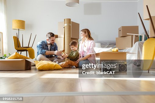 Happy young family unpacking belongings from boxes in new apartment Happy young family unpacking belongings from boxes in new apartment