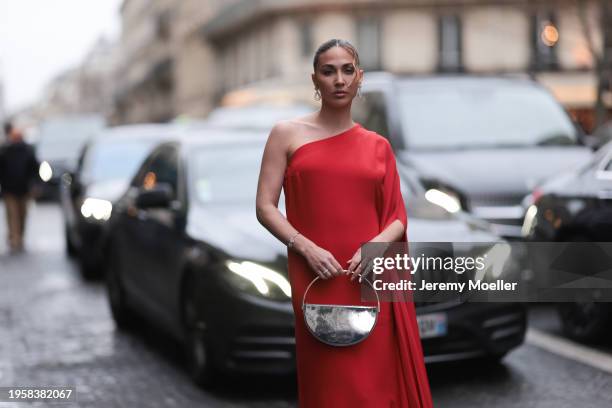 Ann Kathrin Götze is seen wearing a long red dress with a train, gold hoop earrings by Chopard and a silver metallic handbag during the Stephane...