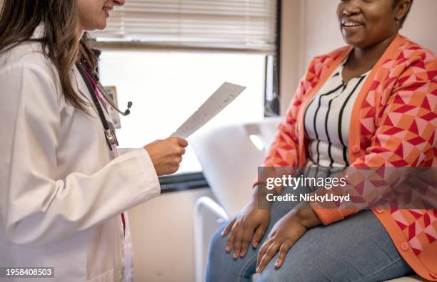 female doctor talking with a smiling patient during a hospital appointment - medical test results stock pictures, royalty-free photos & images