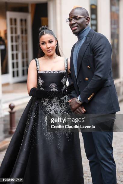 Majda Sakho wears a black decorated maxi dress, black velvet gloves and Mamadou Sakho wears navy blue blazer, blue pants, light blue turtleneck...
