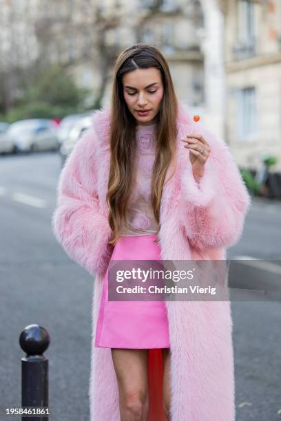 Mara Lafontan with a lollipop wears pink mini skirt, pink faux fur coat, blouse, heels outside Viktor&Rolf during the Haute Couture Spring/Summer...