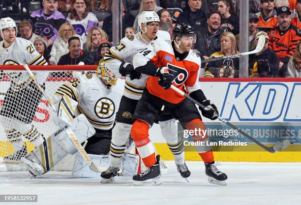 Sean Couturier of the Philadelphia Flyers battles for position in front of goaltender Linus Ullmark of the Boston Bruins with Hampus Lindholm at the...