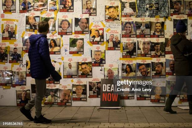 People walk by a wall with photos of hostages held in the Gaza Strip by Hamas during a rally calling for release of all hostages on January 27, 2024...