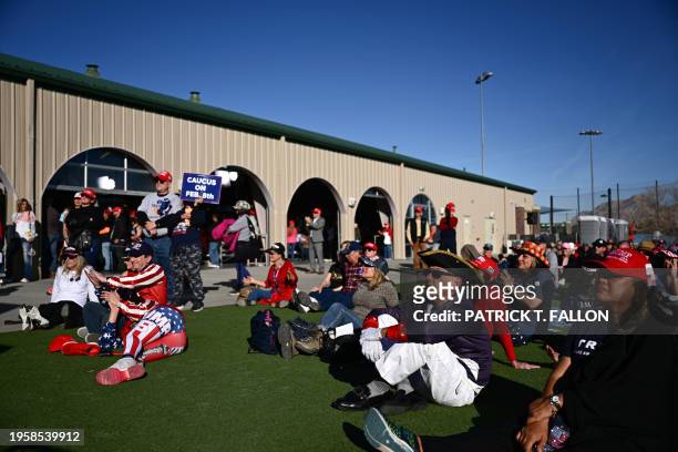 Supporters of former US President and 2024 presidential hopeful Donald Trump watch his speech on an screen outside a Commit to Caucus Rally in Las...