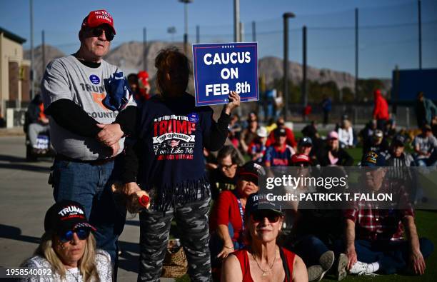 Supporters of former US President and 2024 presidential hopeful Donald Trump watch his speech on an screen outside a Commit to Caucus Rally in Las...