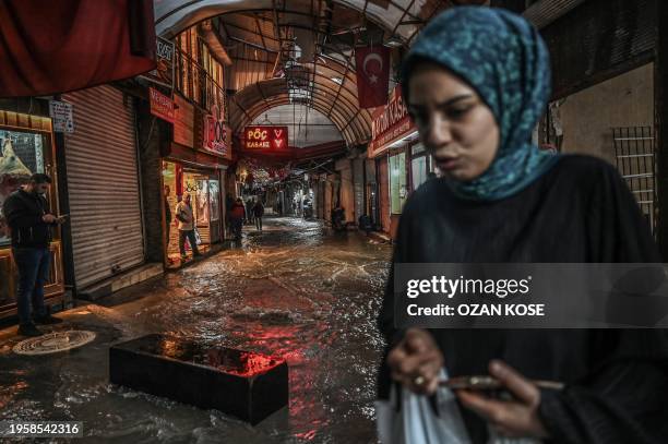 Woman walks past flood waters at the Uzuncarsi Bazzar following heavy rains, eleven months after a 7.8-magnitude earthquake jolt and aftershocks...