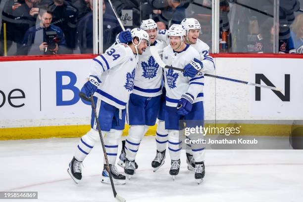 Auston Matthews, Simon Benoit, Jake McCabe and Matthew Knies of the Toronto Maple Leafs celebrate a third period empty net goal against the Winnipeg...