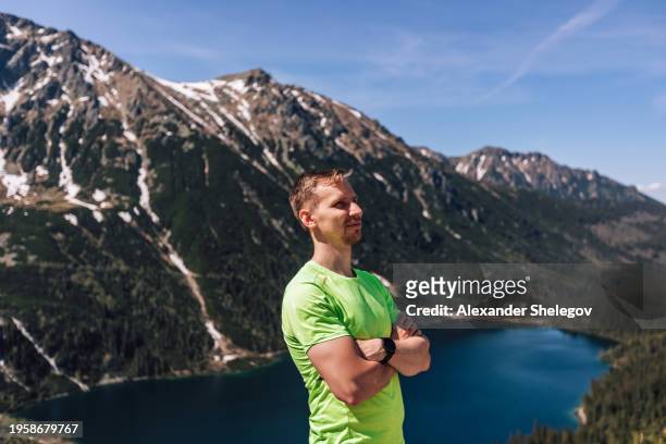 person doing hiking with green sportswear outdoors. lifestyle photography of real people, tourism concept with smart watch. male portrait of man, who traveling in mountains. - tatra national park stock pictures, royalty-free photos & images