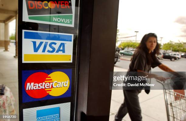 Shopper passes a shop door advertising acceptance of purchases with Master Card, Visa, and other credit cards April 29, 2003 in Bakersfield,...