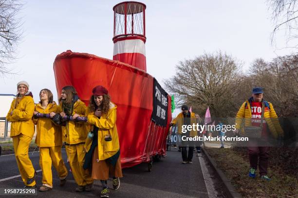 Climate activists march alongside Greta, a 20-foot bright red lightship, during a protest against private jet flights and the proposed expansion of...