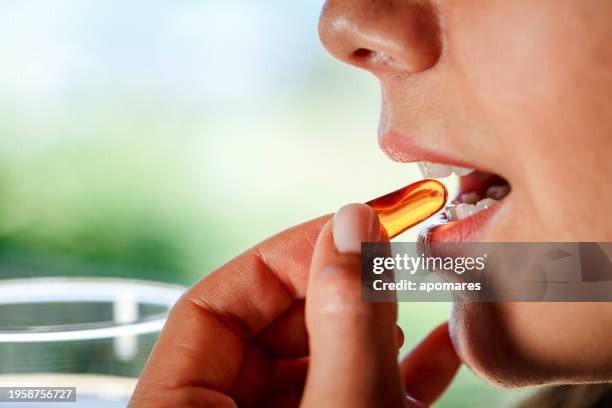 close-up of hispanic young woman ready taking fish oil pill - vitamine d stockfoto's en -beelden