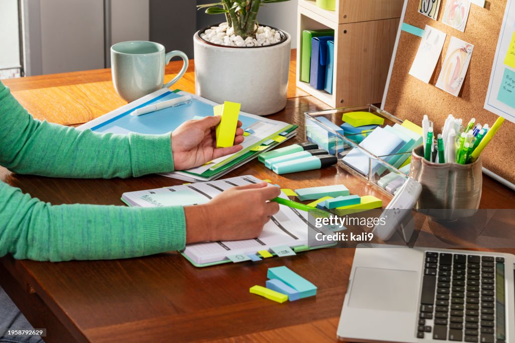 Hands of Asian woman at desk, holding page markers