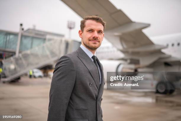 caucasian businessman standing in front of an airplane - turismo responsable fotografías e imágenes de stock