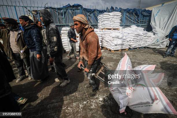Displaced Palestinians receive food aid at the United Nations Relief and Works Agency for Palestine Refugees center in Rafah in the southern Gaza...
