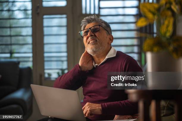 old entrepreneur with neckache working from home - neck pain stock pictures, royalty-free photos & images