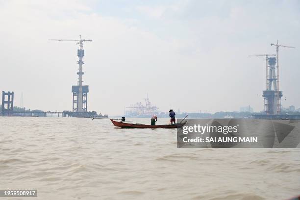 Fishermen on a boat haul in their net in the Yangon river in Yangon on January 28, 2024.