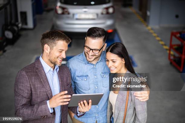 happy manager and young couple using touchpad in auto repair shop. - touchpad stockfoto's en -beelden