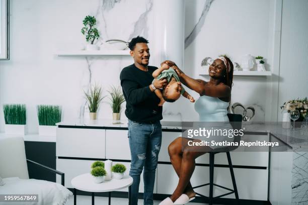 african black family enjoying playing with baby son at home - human arm photos et images de collection