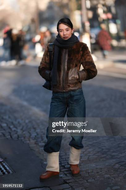 Guest is seen outside Hermes show wearing a grey scarf, brown bomber fur jacket and black pair of jeans and brown boots during the Menswear...