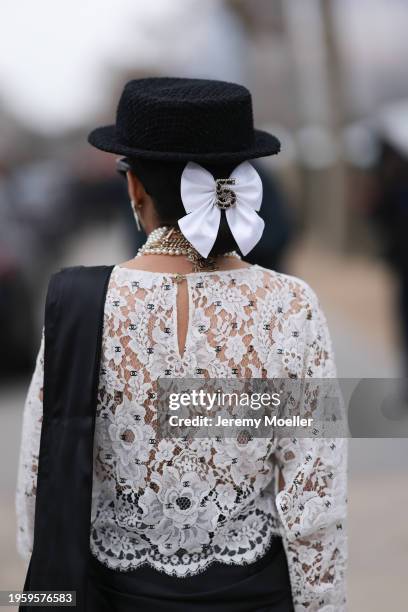 Snehal Babani is seen wearing a white hat with black sunglasses, pearl earrings, pearl necklaces by Chanel, a black lace top by Chanel, a one-sleeved...