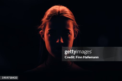 Young Good Looking Woman With Her Hair Tied Up Watching Right Into The Camera Illuminated In Red Light Young Good Looking Woman With Her Hair Tied Up Watching Right Into The Camera Illuminated In Red Light