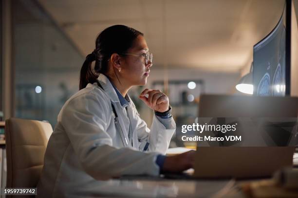 computer, brain scan and doctor asian woman in hospital at night for medical, research or learning. healthcare, thinking and screen with young medicine professional in office of clinic for neurology - electronic medical record stockfoto's en -beelden