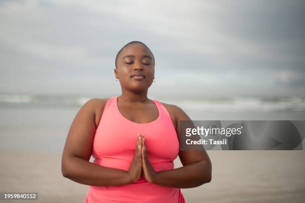 meditation, prayer hands and plus size black woman at a beach for peace, zen or mental health wellness. mindfulness, healing or african lady person at sea for gratitude, balance or holistic breathing - healing prayer images stock pictures, royalty-free photos & images