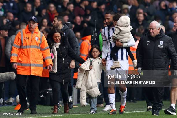 West Bromwich Albion's English defender Kyle Bartley helps take members of his family away from an area of the ground where trouble has broken out...
